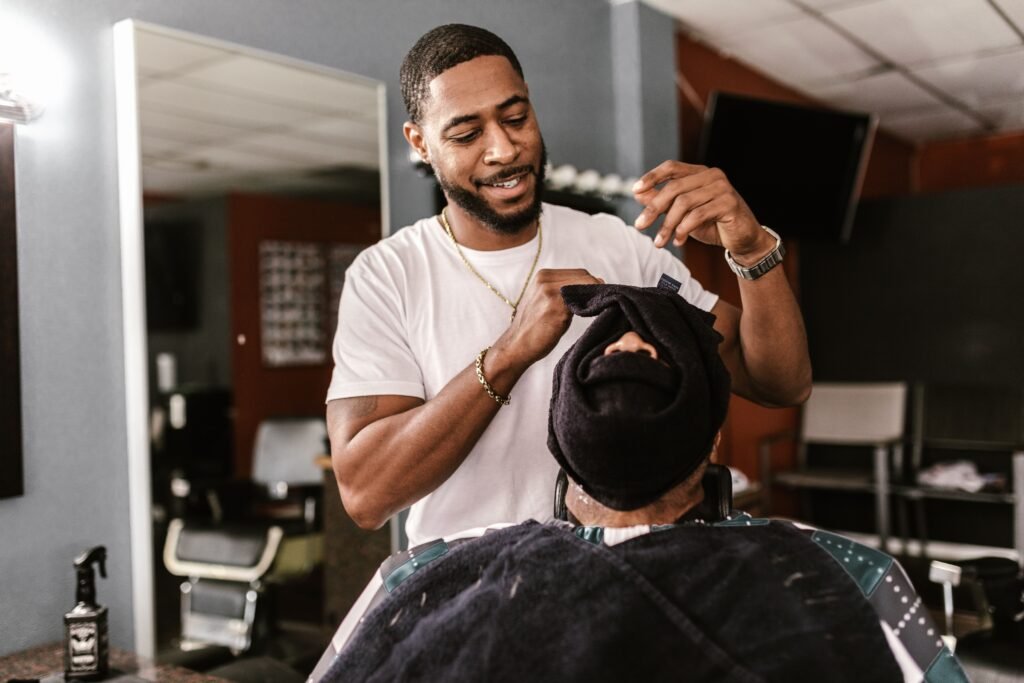 Barber skillfully using a hot towel on a customer in a barbershop setting.